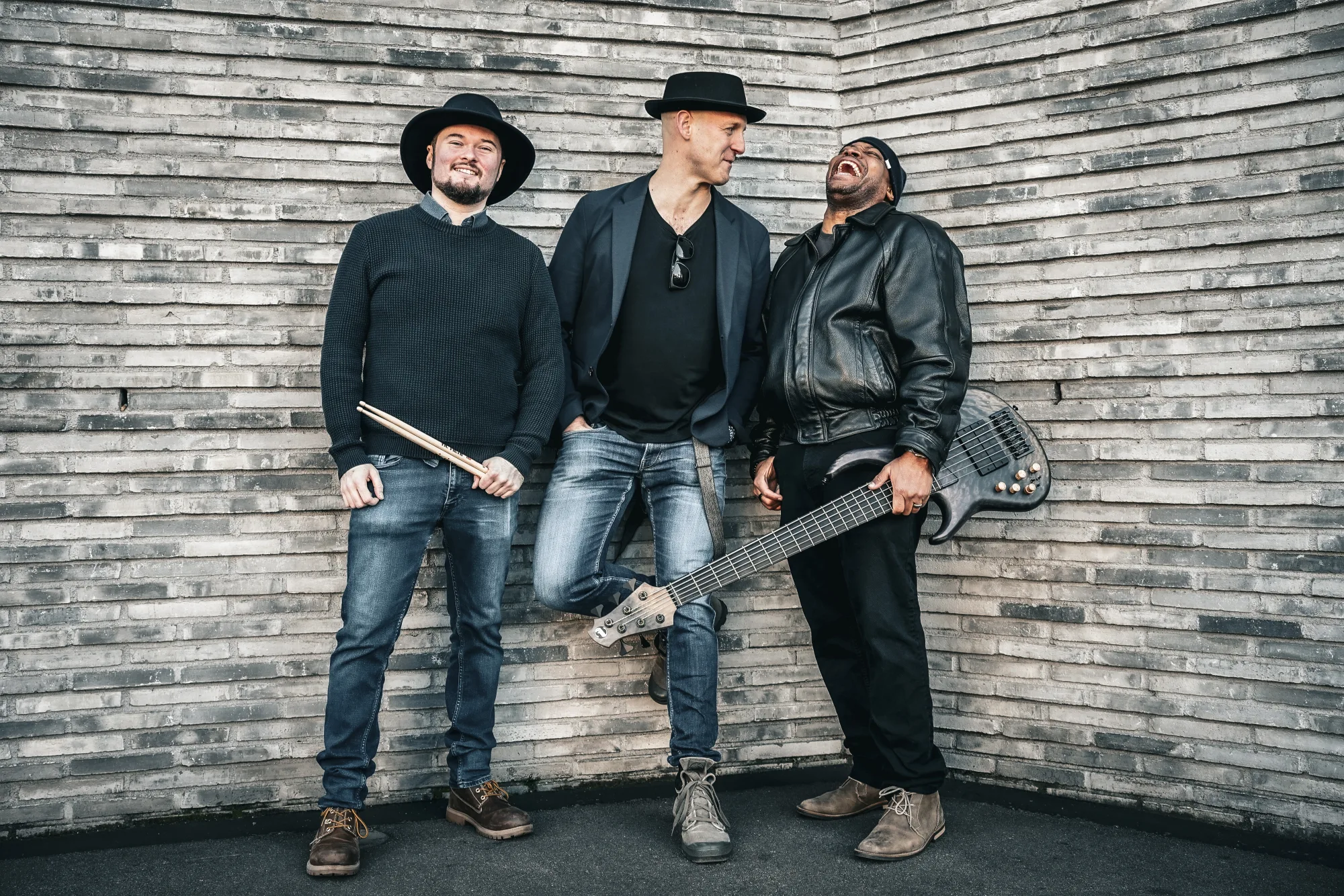Mike Low standing with his band in front of a stone wall
